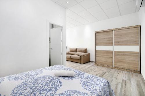 biała sypialnia z łóżkiem i kanapą w obiekcie Apartamento Venus 1 w mieście Conil de la Frontera