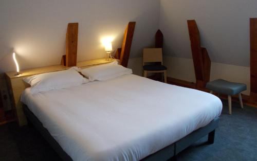 a bedroom with a large white bed and a chair at Logis Hotel De La Poste in Saint-Sauves- dʼAuvergne