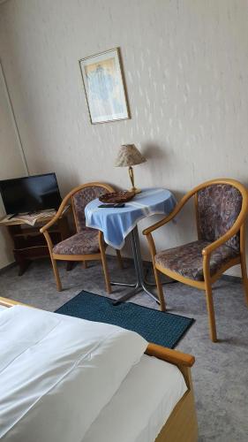 Habitación con 2 sillas y mesa con lámpara. en Pension Backhaus, en Waldeck