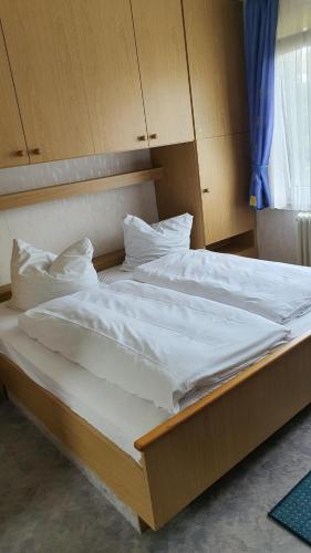duże łóżko z białą pościelą i poduszkami w obiekcie Pension Backhaus w mieście Waldeck