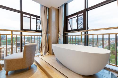a large white bath tub in a room with windows at TRUE Go hotel in Chengdu