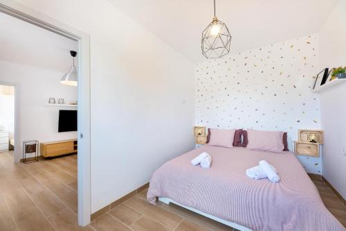 a bedroom with a pink bed with two white towels at Es Cos in Algaida