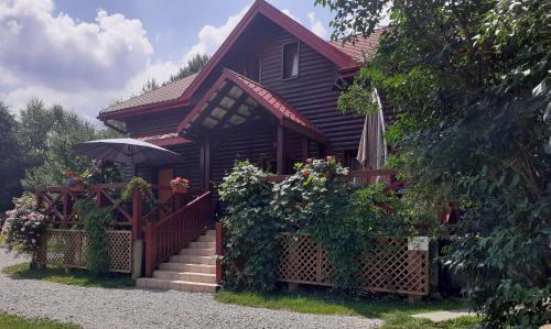 a wooden house with a staircase and an umbrella at Leśne Berdo Przysłup in Cisna