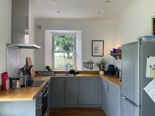 a kitchen with gray cabinets and a sink and a window at Arran School House - Blackwaterfoot, Isle of Arran in Blackwaterfoot