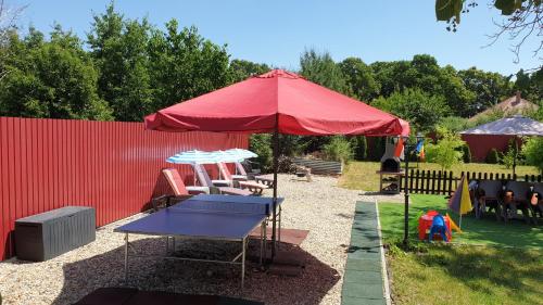 a red umbrella with a table and chairs under it at Casa Lyna in Gyomaendrőd