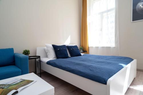 een slaapkamer met een bed met blauwe lakens en een blauwe stoel bij Blue Ribbon Apartment in Boedapest
