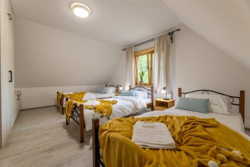 a bedroom with two beds with yellow blankets and a window at BRZOZOWY SZELEST in Ustrzyki Dolne