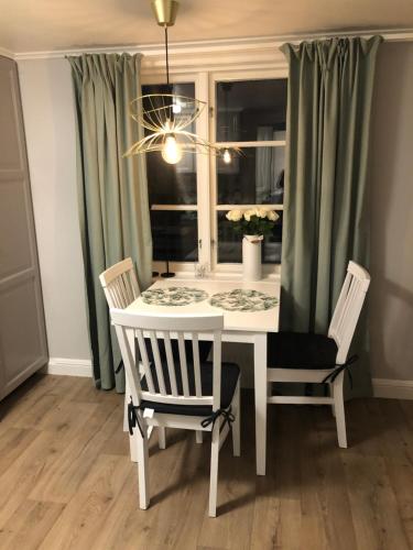 a white dining room table with two chairs and a window at Rådstugugatan 32 in Nora