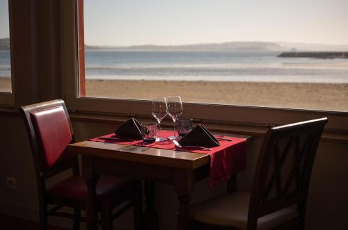 a table with wine glasses and a view of the beach at Hôtel & Restaurant de la Plage in Crozon