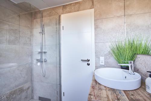 een badkamer met een douche, een wit bad en een wastafel bij Smart Resorts Haus Opal Ferienwohnung 404 in Winterberg