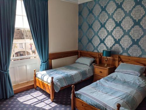 two beds in a room with a window and curtains at The Londesborough Arms bar with en-suite rooms in Market Weighton