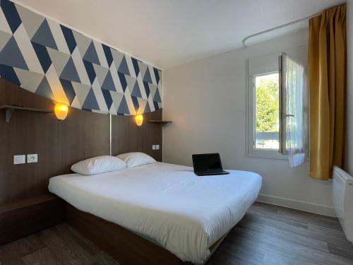 a bedroom with a bed with a laptop on it at Kyriad Direct Val de Reuil in Val de Reuil