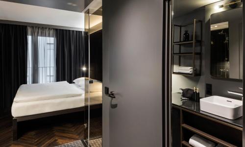 a bedroom with a bed and a sink and a mirror at Hotel ROMY by AMANO in Berlin