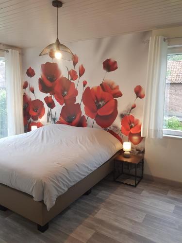 a bedroom with a bed with red flowers on the wall at Mary's Poppies - Bed & Breakfast in Blandain