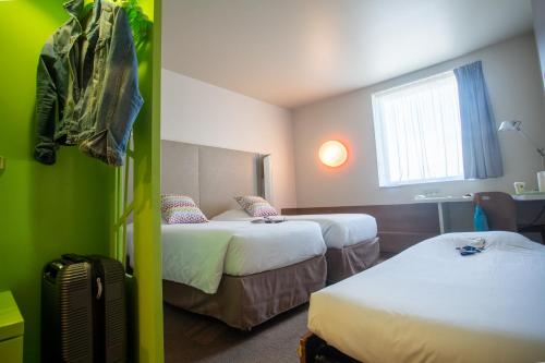 a hotel room with two beds and a window at Campanile Carcassonne Est - La Cité in Carcassonne