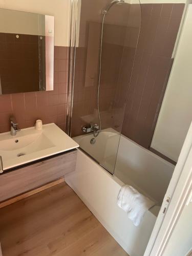 a bathroom with a sink and a tub and a shower at Les résidences du port appartements meublés in Porto Ota