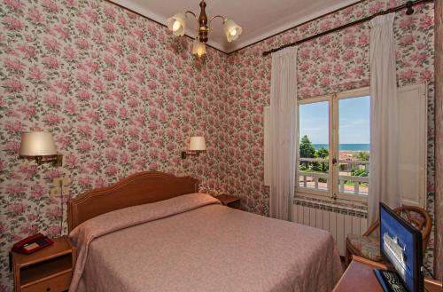1 dormitorio con cama y ventana en Hotel Villa Flores, en Marina di Pietrasanta