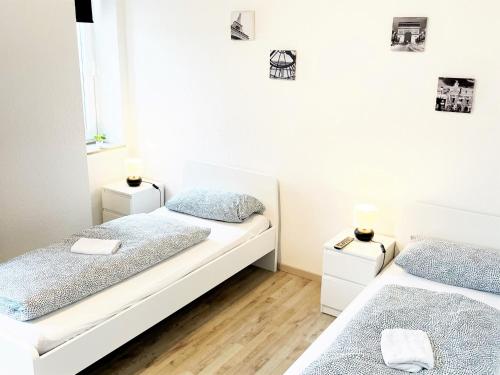 two beds in a room with white walls and wooden floors at Work & Stay im Herzen von Celle in Celle