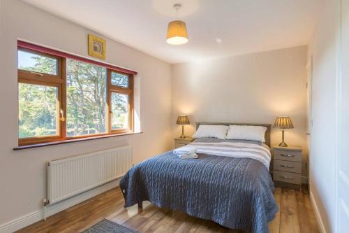 a bedroom with a bed and two windows at The Villa - On the Waterford Greenway Kilmacthomas in Kilmacthomas