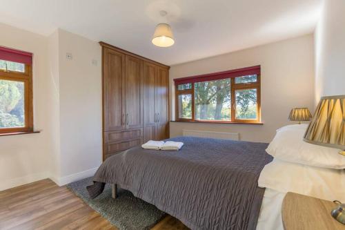 a bedroom with a large bed and two windows at The Villa - On the Waterford Greenway Kilmacthomas in Kilmacthomas