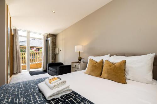 a bedroom with a large white bed and a balcony at Lanelay Hall Hotel & Spa in Hensol