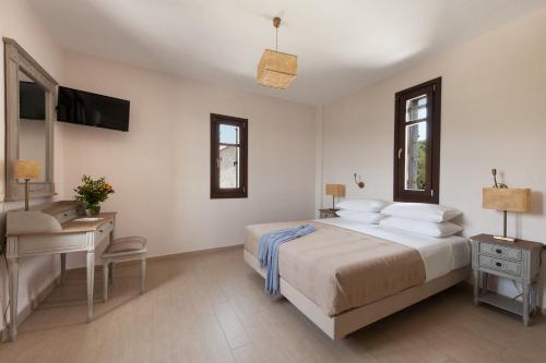 a white bedroom with a bed and a desk and a television at Kamares Villas in Kamáres