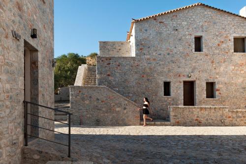 a woman walking up the stairs of a brick building at Kamares Villas in Kamáres