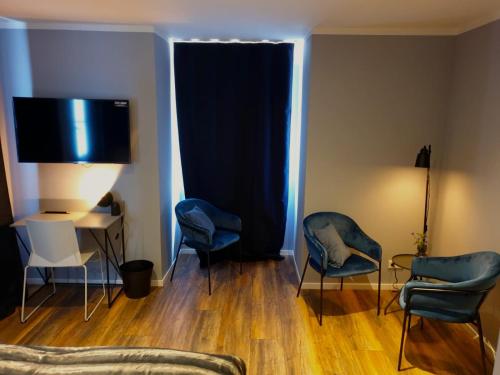 a living room with blue chairs and a television at Hotel Kornblume in Haundorf