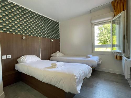 two beds in a small room with a window at Kyriad Direct Val de Reuil in Val de Reuil