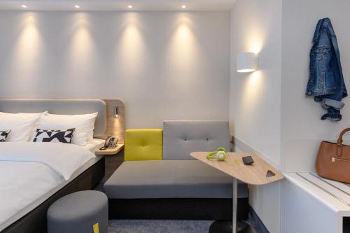 a hotel room with a bed and a chair at Holiday Inn Express Göttingen by IHG in Göttingen