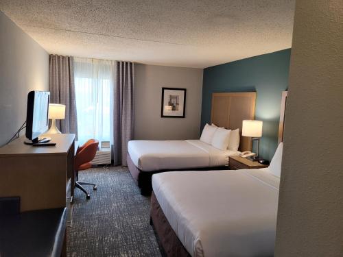 a hotel room with two beds and a desk and a tv at Comfort Inn & Suites Alexandria West in Alexandria