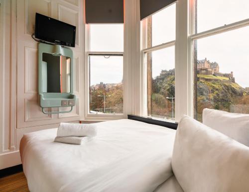 a bedroom with a large white bed with a large window at easyHotel Edinburgh in Edinburgh