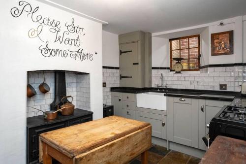 eine Küche mit weißen Geräten und einem Holztisch in der Unterkunft Fagins Den Themed Holiday Cottage Broadstairs in Broadstairs