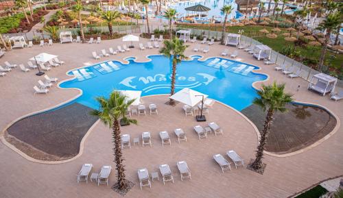 einen Blick über einen Pool mit Stühlen und Palmen in der Unterkunft Waves Aqua Resort in Kenitra