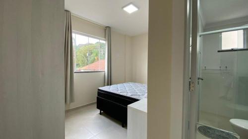 una camera con letto e un bagno con finestra di Manchester 106 A · Lindo e novíssimo Apartamento na praia Bombas. a Bombinhas