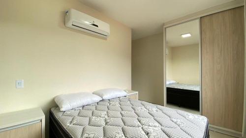 una camera con letto e specchio di Manchester 106 A · Lindo e novíssimo Apartamento na praia Bombas. a Bombinhas