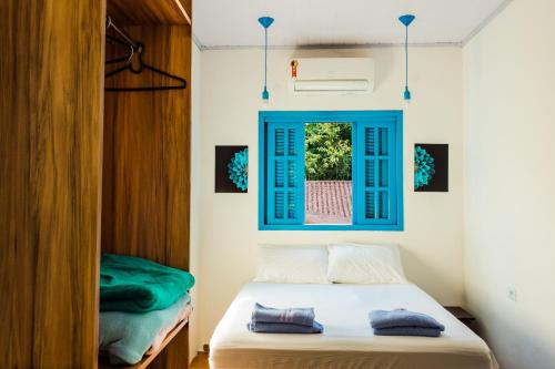 a bedroom with a bed and a blue window at Flow Hostel Juquehy in Juquei