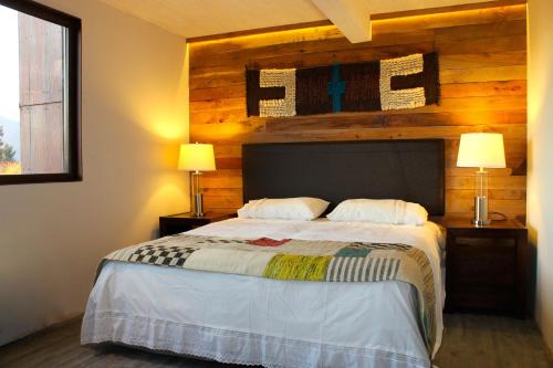 a bedroom with a bed with a wooden wall at Rangi Pucon in Pucón