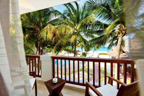 a balcony with a view of the beach and palm trees at Amani Boutique Hotel - Small Luxury Hotels of the World in Paje