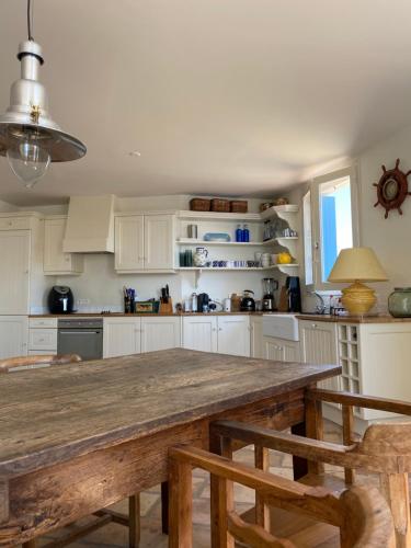 een keuken met witte kasten en een houten tafel bij VillaDorien by Viglamo in Le Barcarès