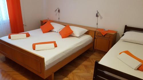 - 2 lits dans une chambre avec des oreillers orange dans l'établissement Apartman Marija, à Senj