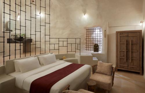a bedroom with a bed and a chair and a tub at White Pearl Cavalieri in Imerovigli