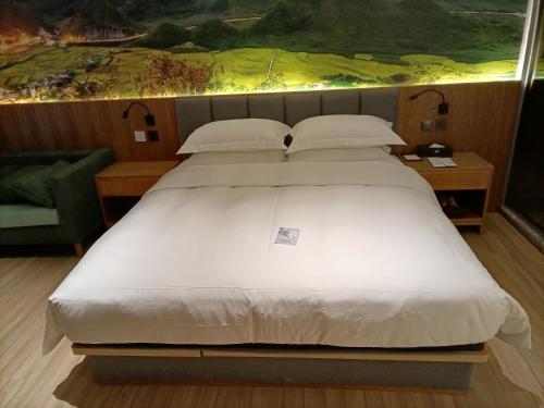 a large white bed in a room with a painting at TRUE Go hotel in Chengdu