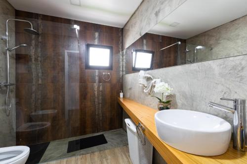 uma casa de banho com um lavatório, um chuveiro e um WC. em As Casas da Margarida na Ribeira Grande