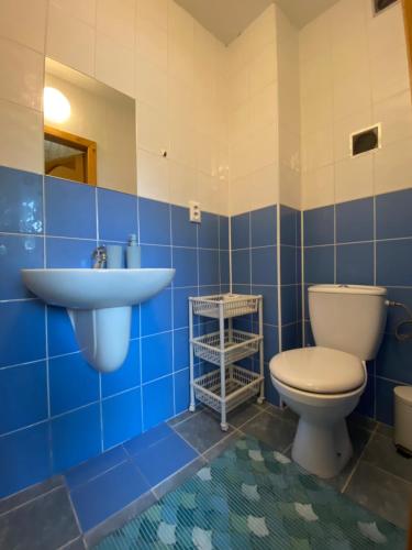 a blue tiled bathroom with a toilet and a sink at Penzion pod Brehom in Terchová