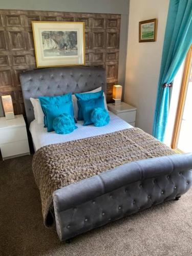 a bedroom with a large bed with blue pillows at Balmaha Lodges and Apartments in Balmaha