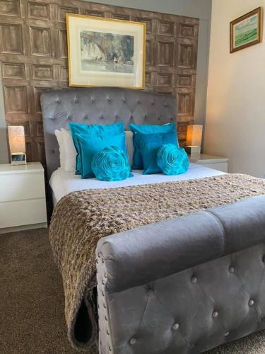 a bedroom with a large bed with blue pillows at Balmaha Lodges and Apartments in Balmaha