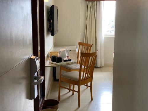 a room with a chair and a table with a coffee maker at Kastel Manibu Recife - Boa Viagem in Recife