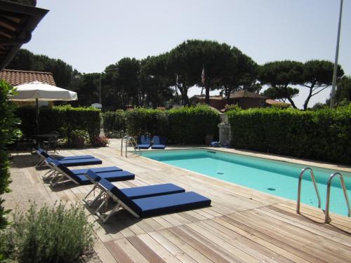 a swimming pool with blue lounge chairs next to it at Hotel Villa Smeraldo in Orbetello