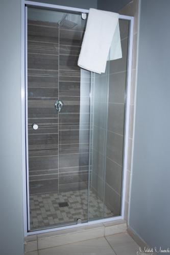 a shower with a glass door in a bathroom at Waterfall View Lodge in Midrand